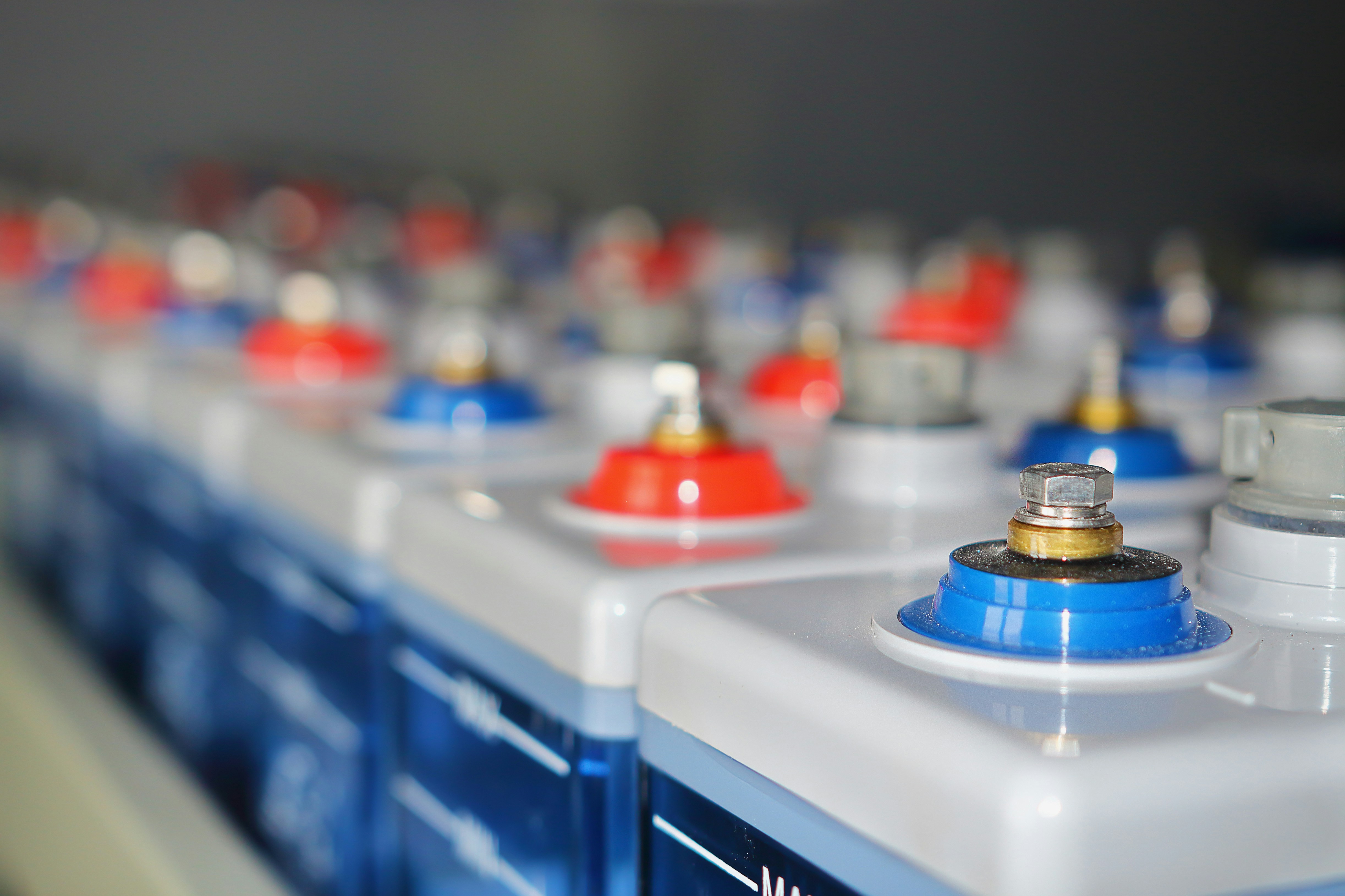 Industrial lead-acid batteries with red and blue terminals ready for reconditioning